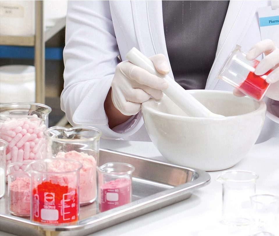 A person in white lab coat stirring something with a spoon.