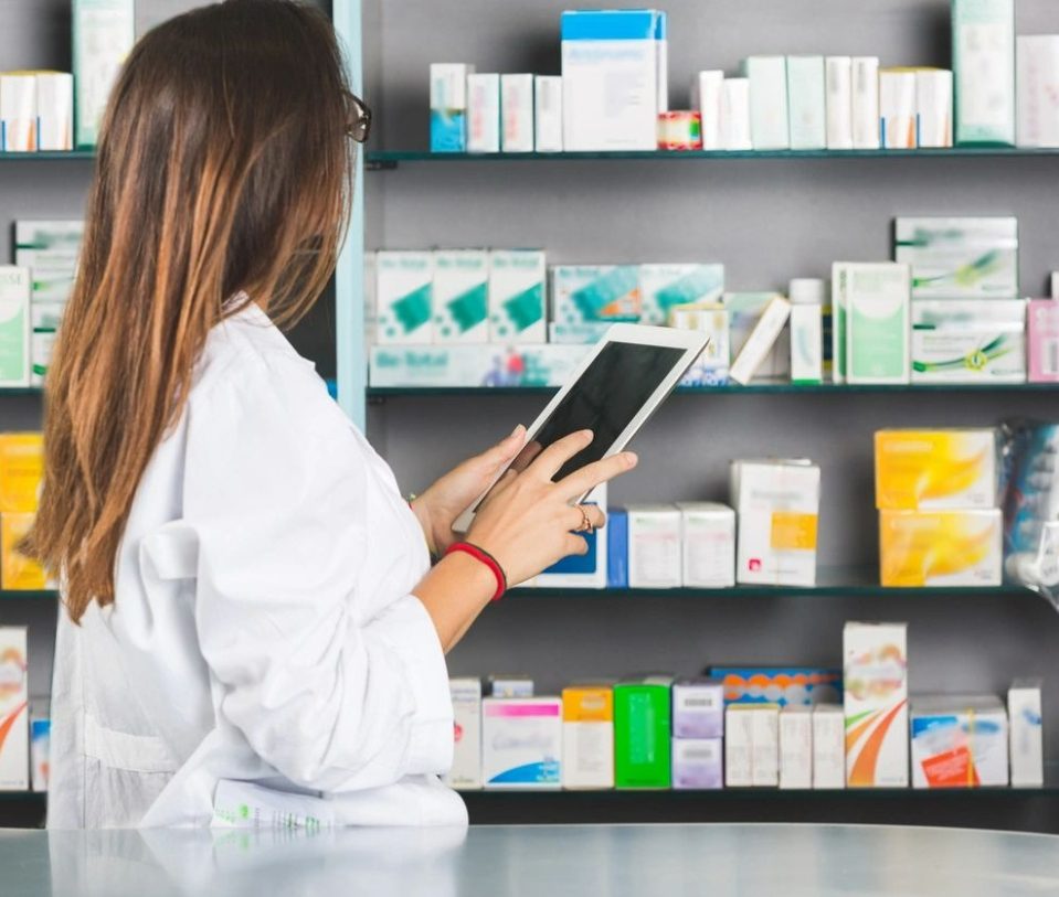 A woman is holding her tablet in front of some shelves.